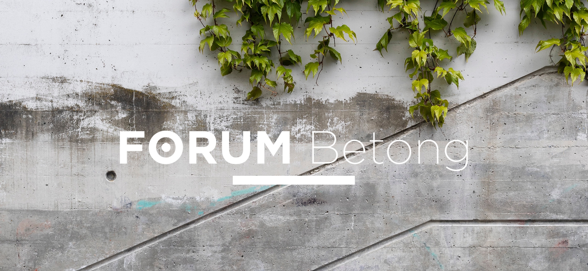 En betongvägg med grönskande växter och Forum Betongs logotyp synlig i centrum.